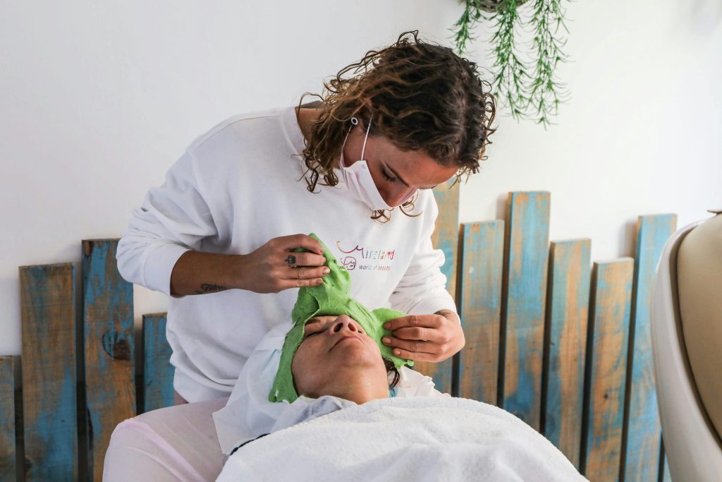 A spa therapist applies a green facial mask during a relaxing spa treatment.