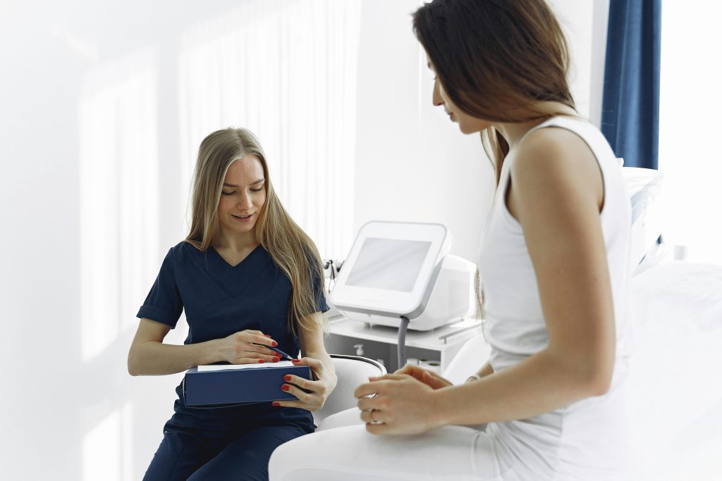 Nurse helping a female patient during a check-up in a modern, bright clinic setting.